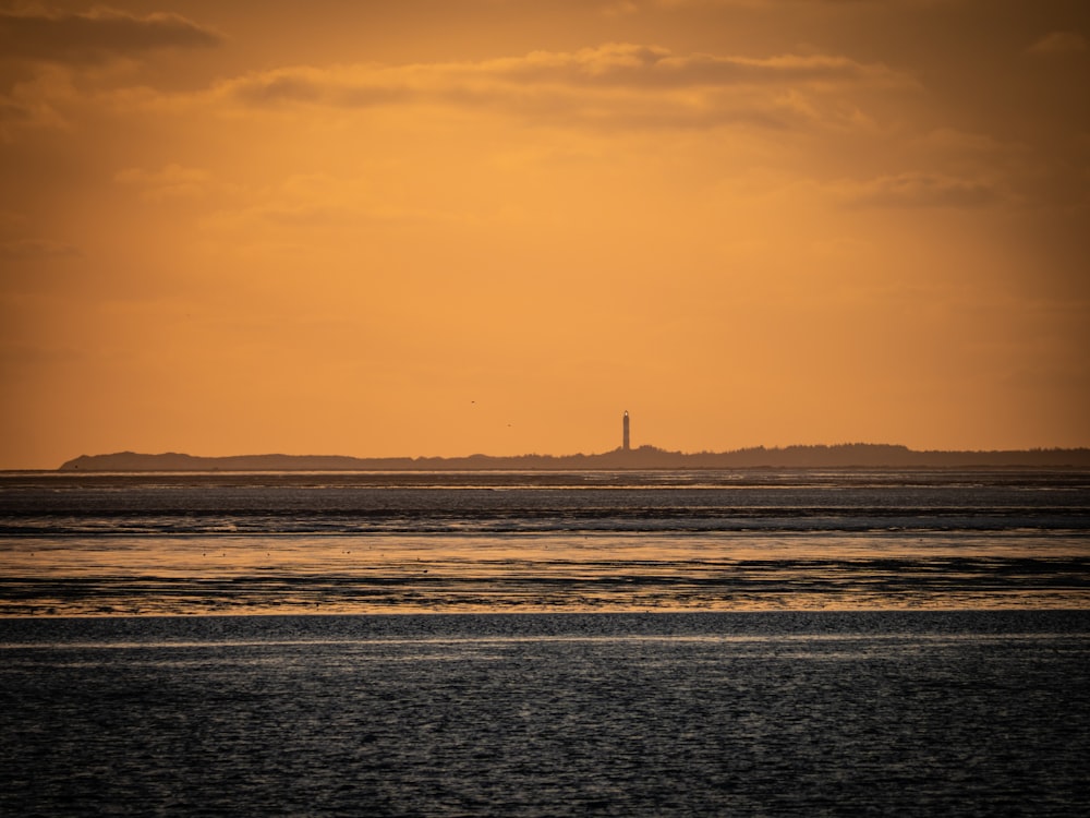 un grand plan d’eau avec un phare au loin