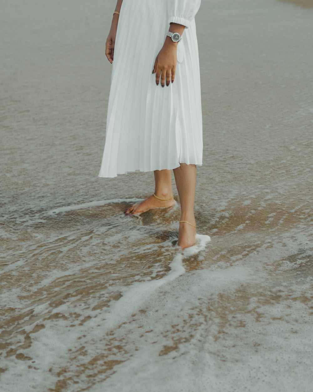 a woman in a white dress standing in the water