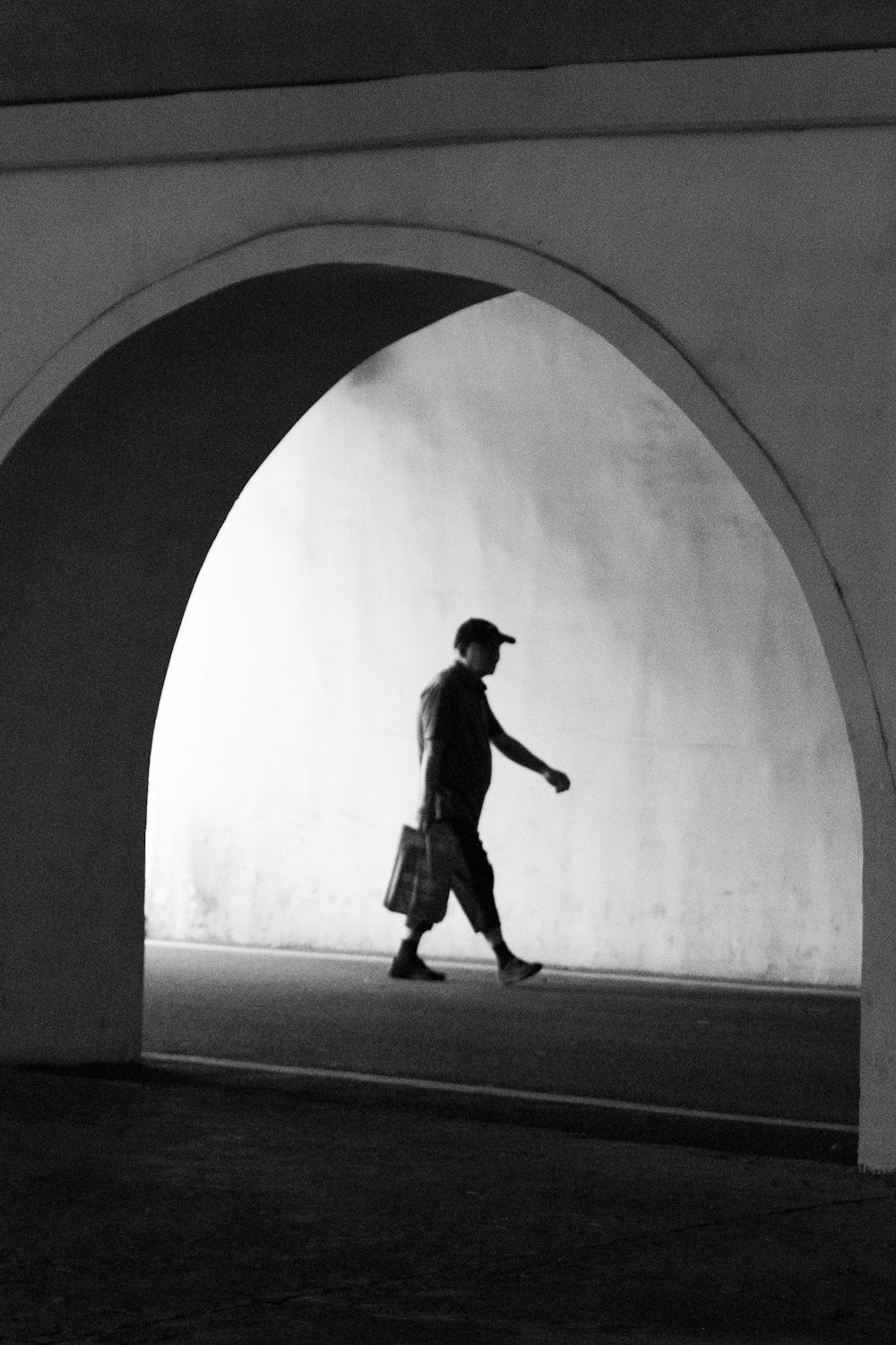 a man walking through a tunnel carrying a bag