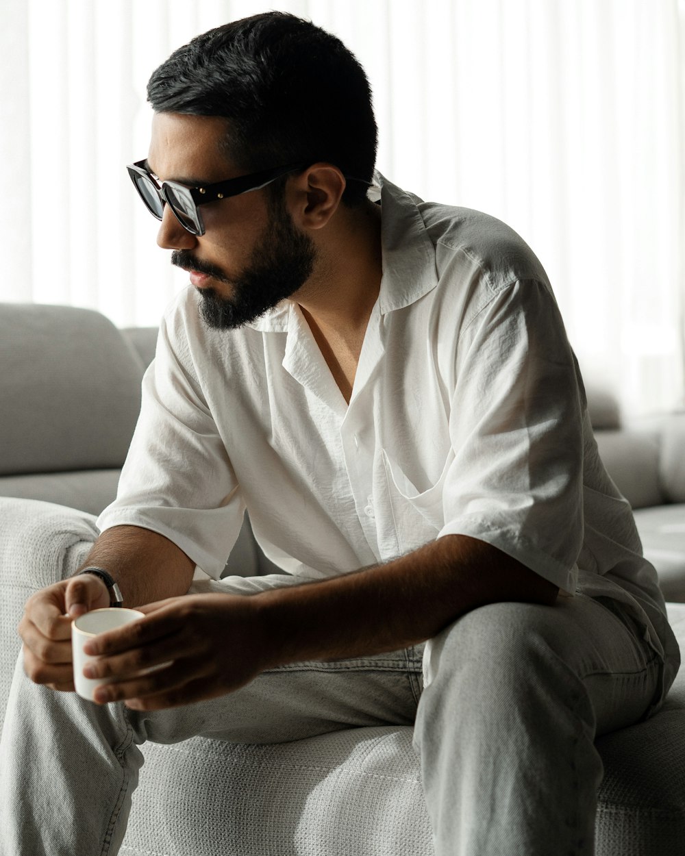 a man sitting on a couch holding a cup