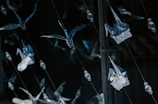 Delicate origami birds arranged in a graceful mobile hanging near a sunlit window.