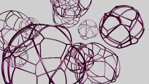 Interconnected geometric wireframe spheres of varying sizes are arranged against a plain background, creating a complex and abstract visual pattern. The structures are composed of purple metallic lines, giving a sense of futuristic or industrial design.
