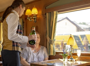 Friendly server pouring wine at a lively restaurant table