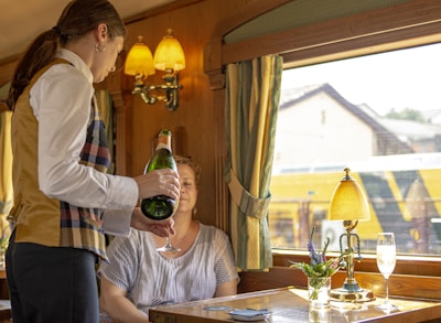 A friendly server pouring wine at a lively restaurant table.