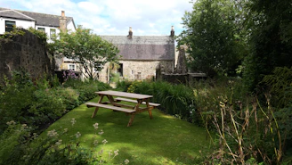 A cozy garden scene with a picnic table scattered with puzzle pieces and fresh fruits.