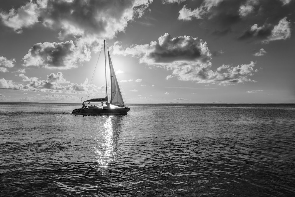 a black and white photo of a sailboat in the ocean