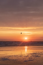A serene beach spot with kite sails in the distance during golden hour.