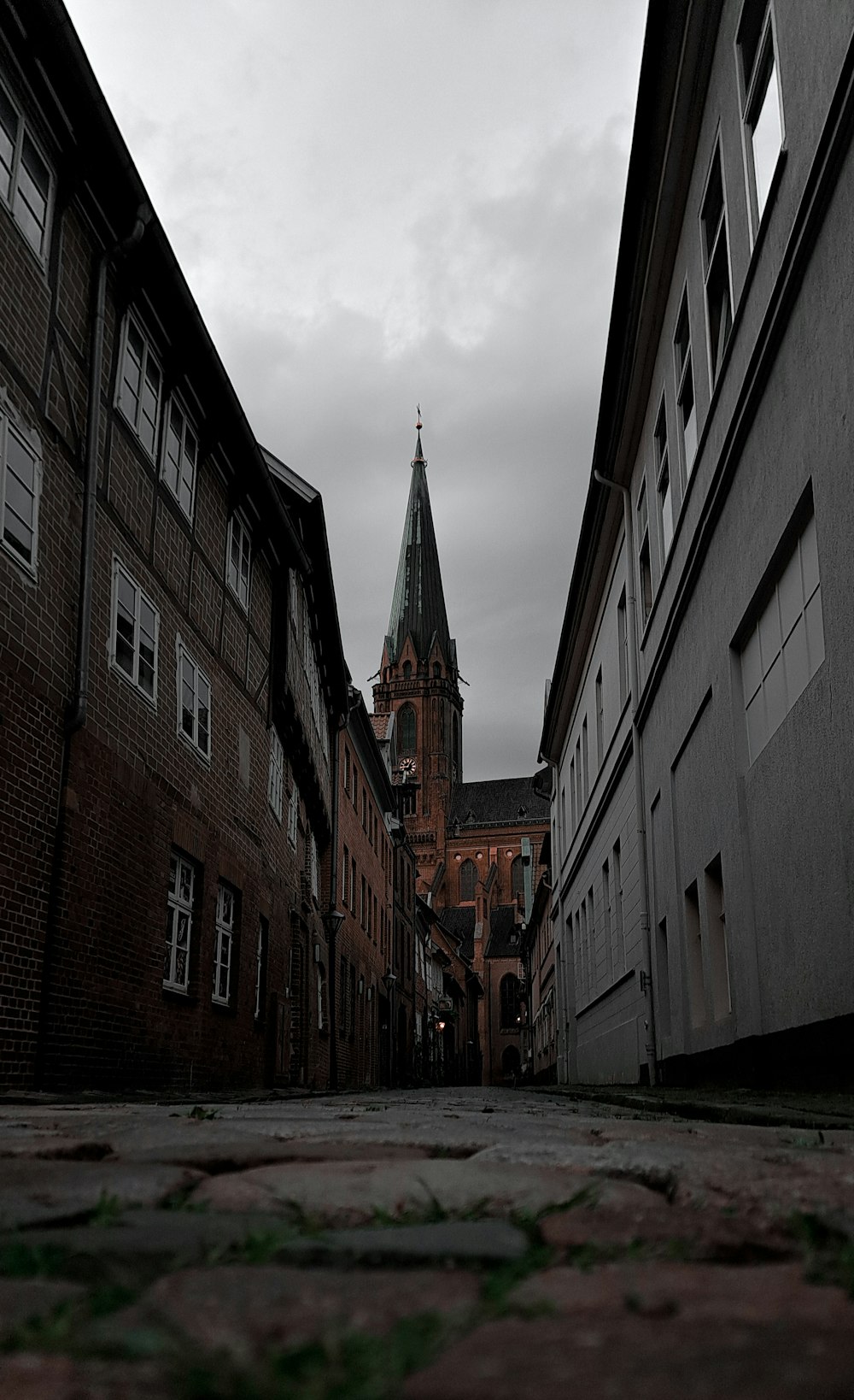 Un callejón oscuro con un campanario de iglesia en el fondo