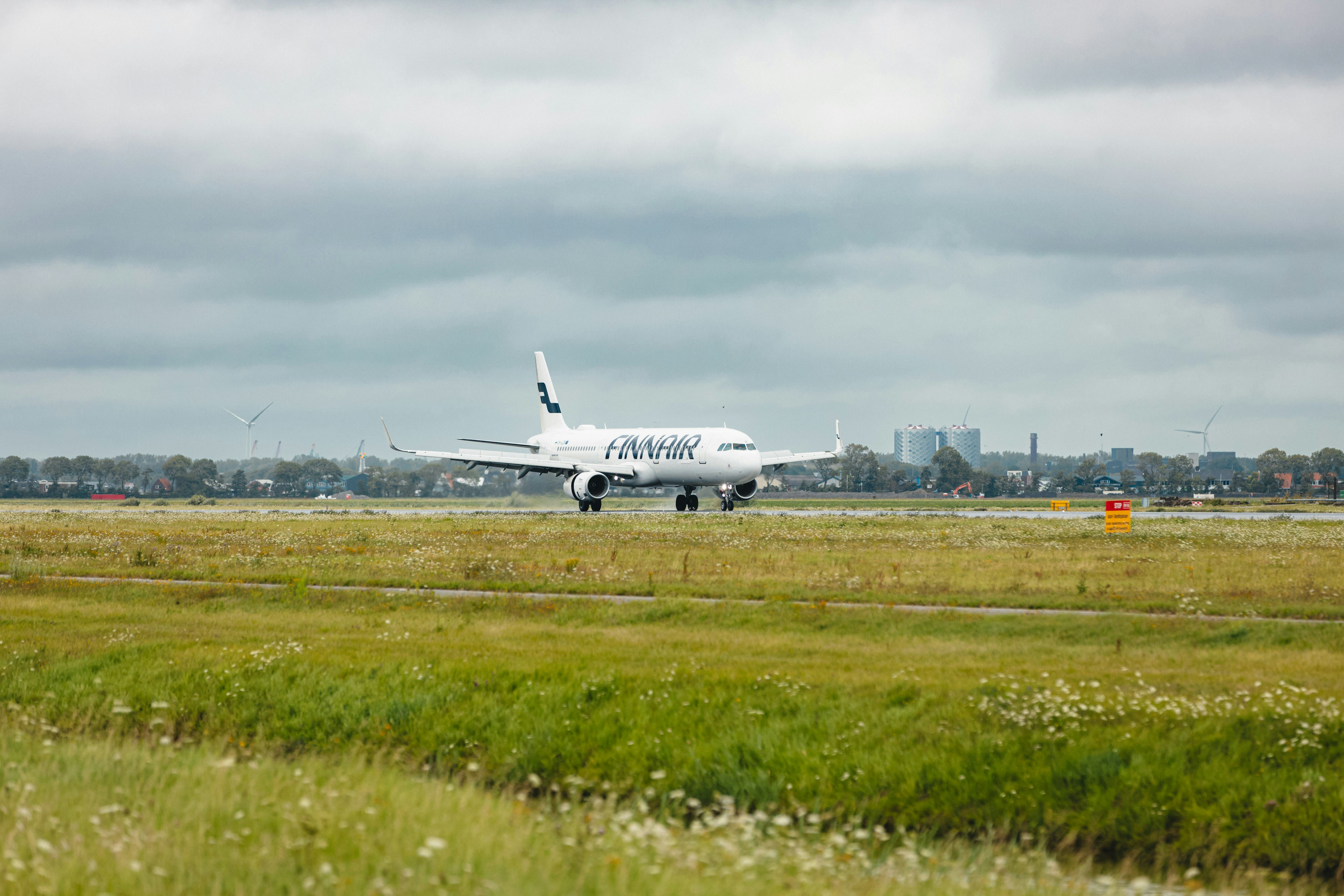 a large jetliner sitting on top of an airport runway, Finnair OH-LZR landing and taxiing on a rainy day at the Polderbaan, Amsterdam Schiphol Airport in the Netherlands.