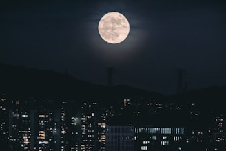 a full moon rises over a city at night