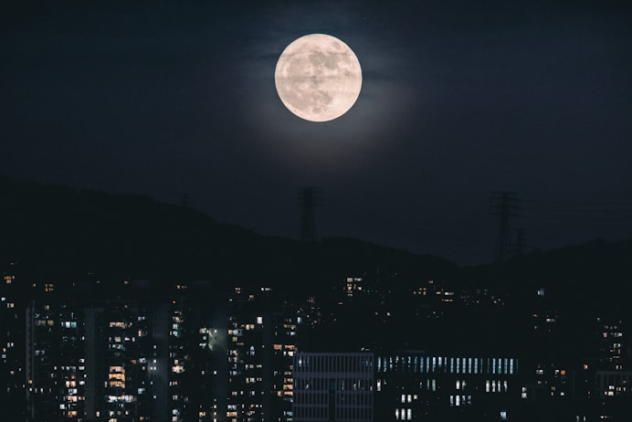 a full moon rises over a city at night