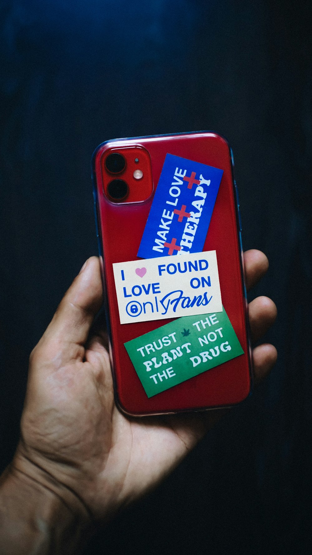 a person holding a red phone case with a sticker on it
