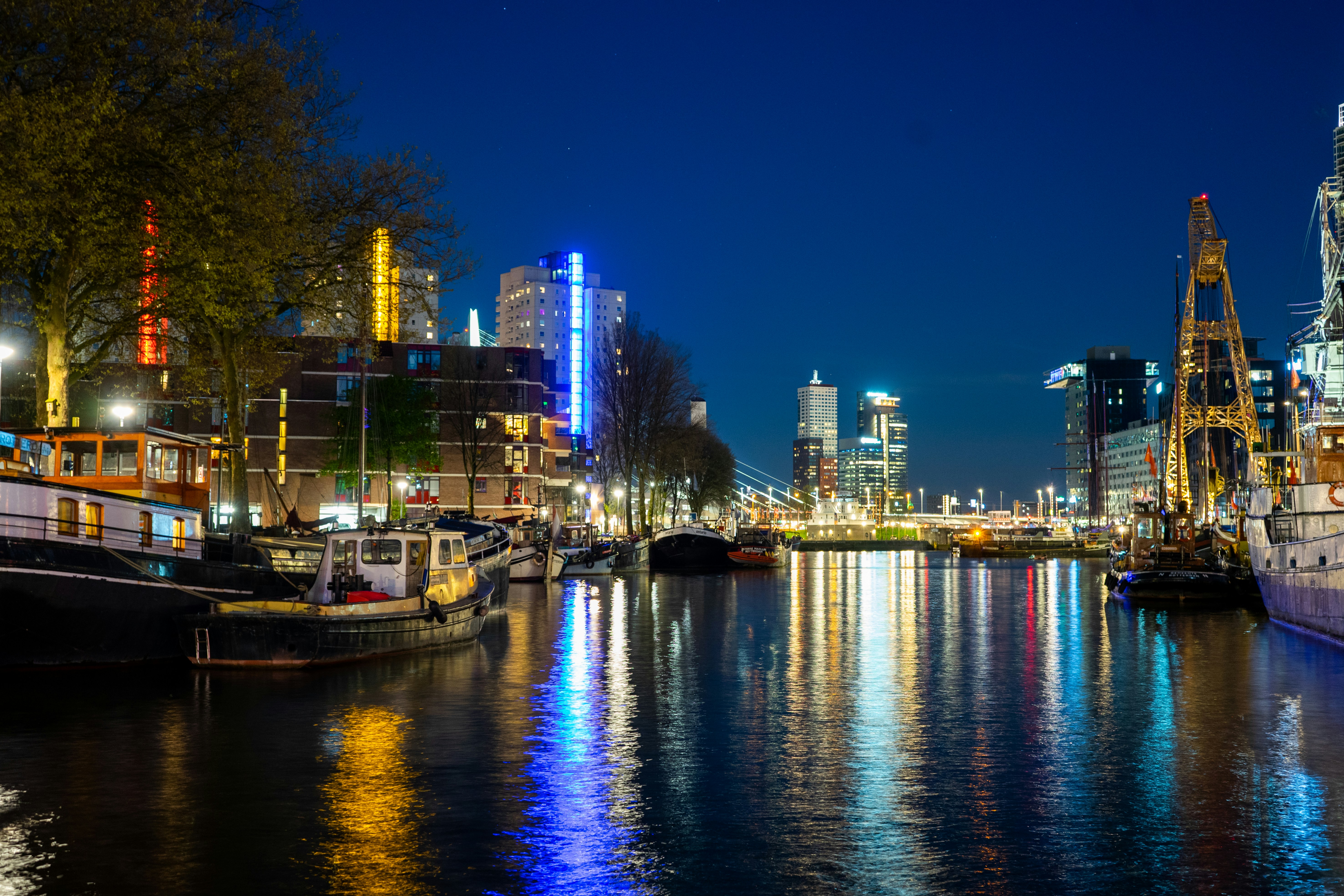 a river filled with lots of boats next to tall buildings