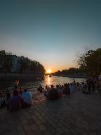 A vibrant photo of travelers enjoying a scenic sunset by the riverside in Tamluk.