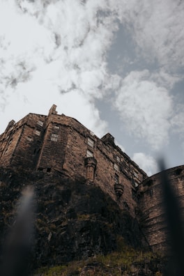 Historic castle ruins perched atop a rocky hill with dramatic clouds overhead.