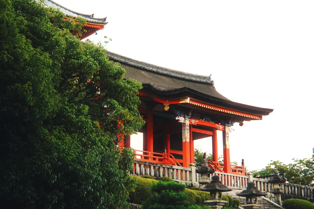 a tall red building sitting next to a lush green forest