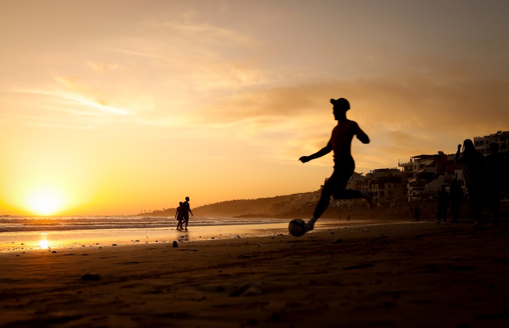 a person kicking a soccer ball on a beach