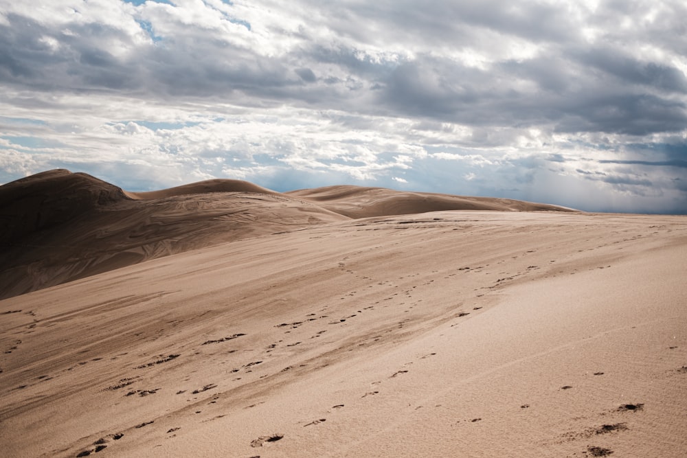 footprints in the sand of a desert under a cloudy sky