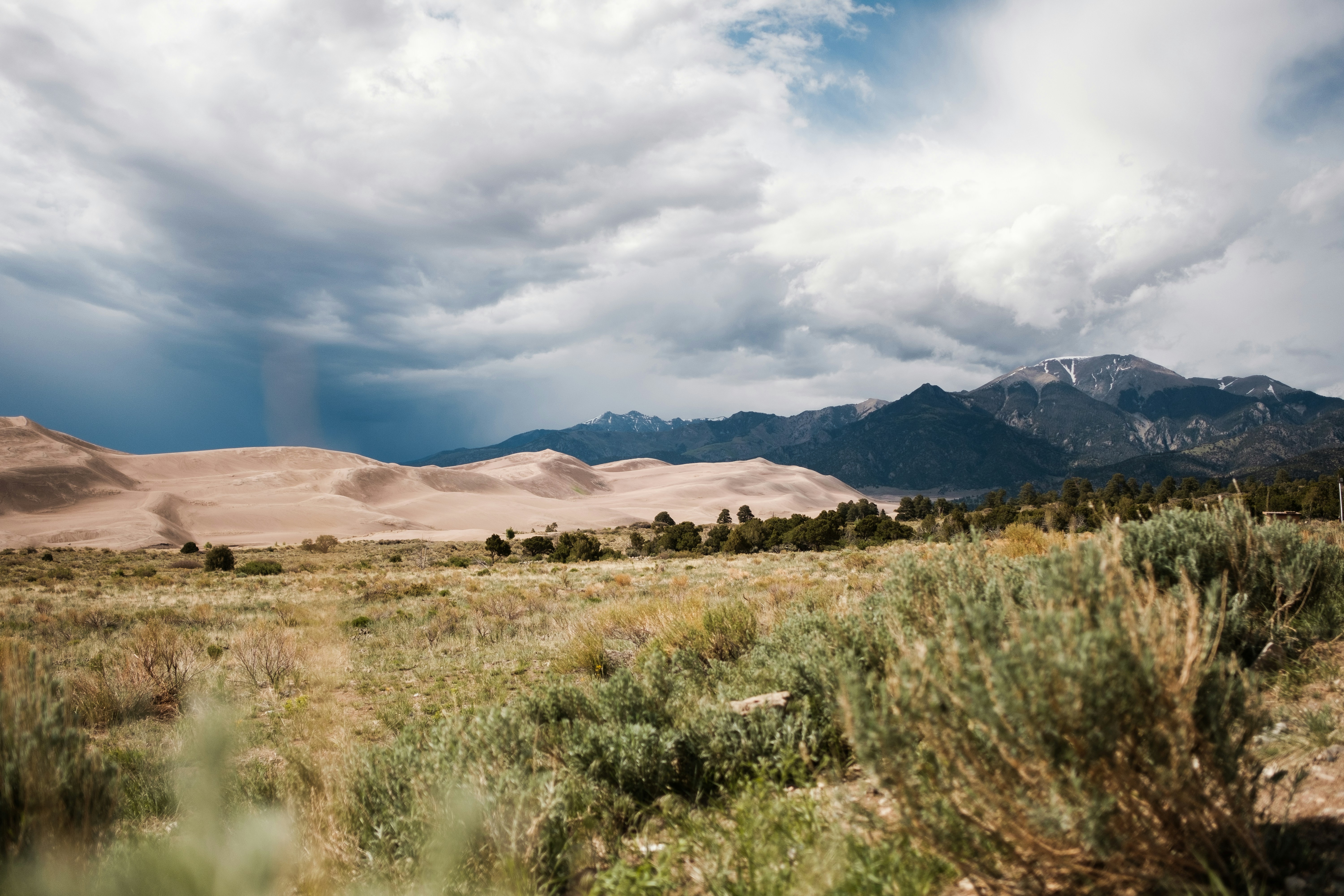a field with mountains in the background under a cloudy sky