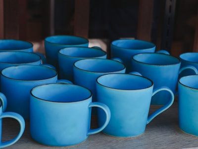 Close-up of elegant ceramic mugs arranged on a wooden shelf.