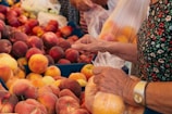 A close-up of hands selecting fresh fruits at a stall.