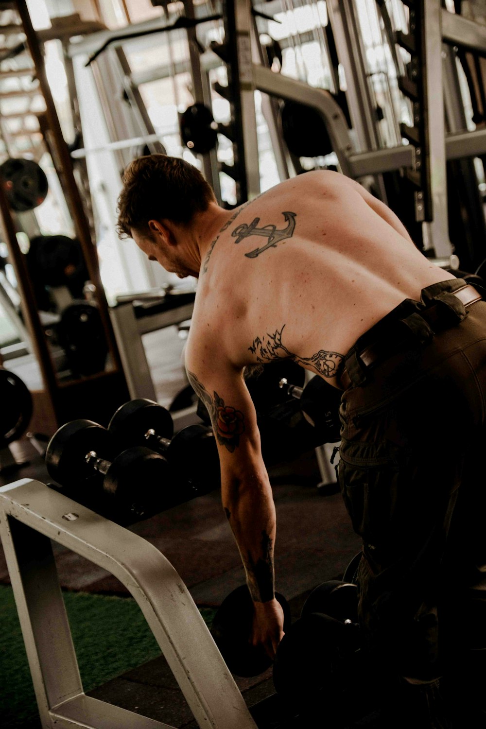a man with a tattoo on his back working out in a gym