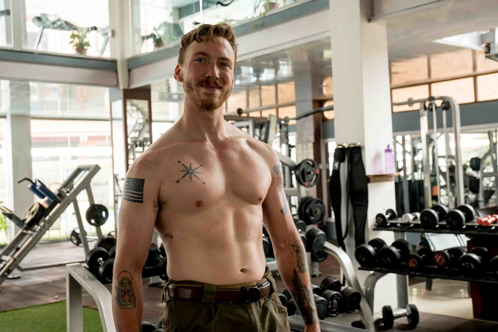 a man with a tattoo on his arm standing in a gym