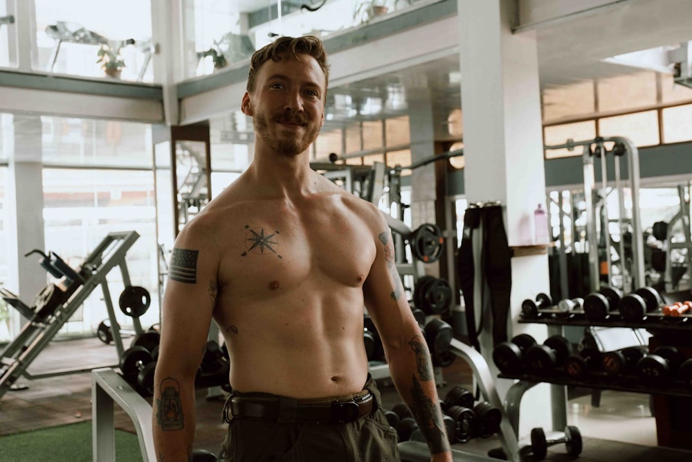 a shirtless man standing in a gym