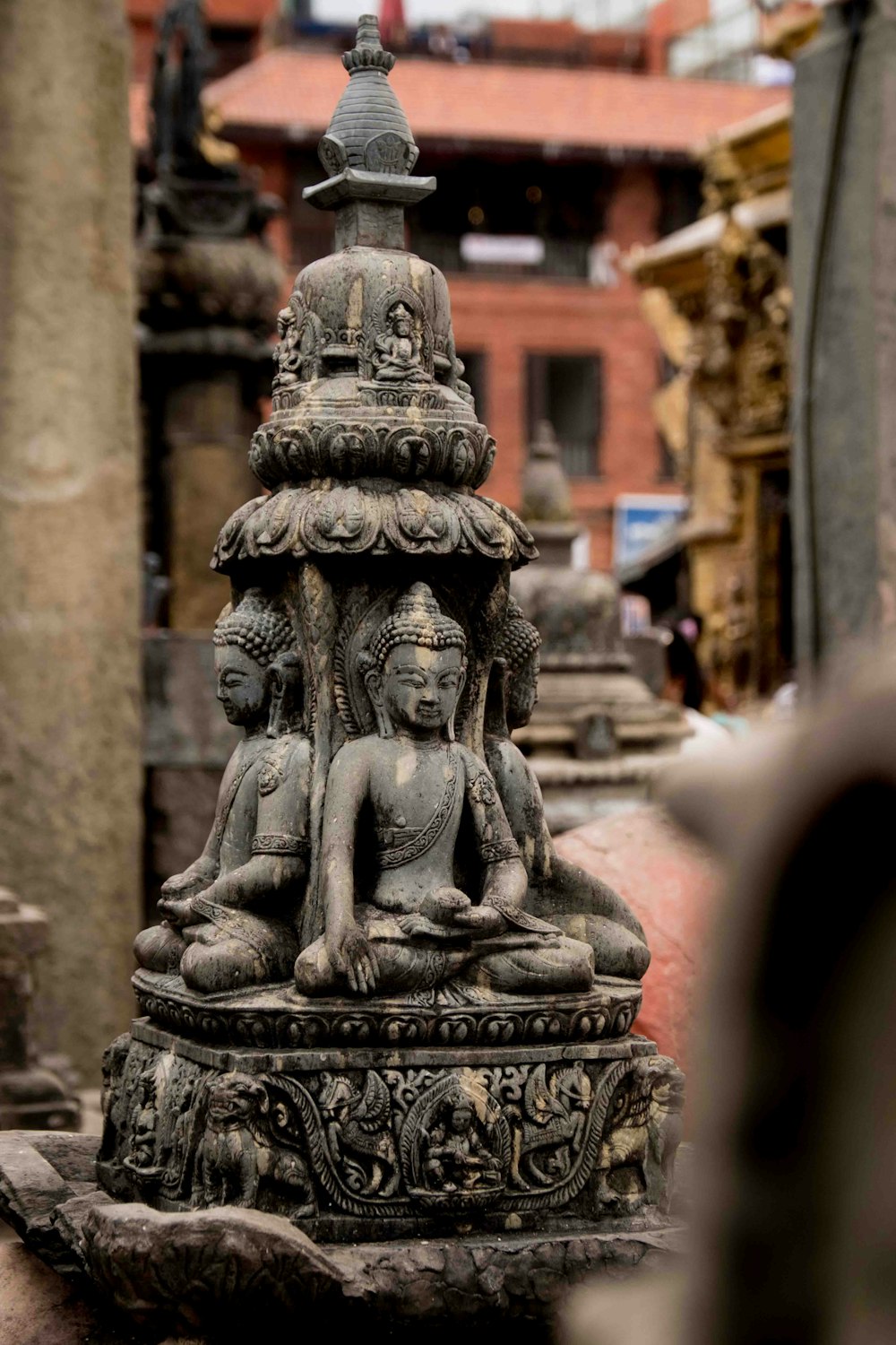 a statue of a buddha sitting on top of a stone pillar