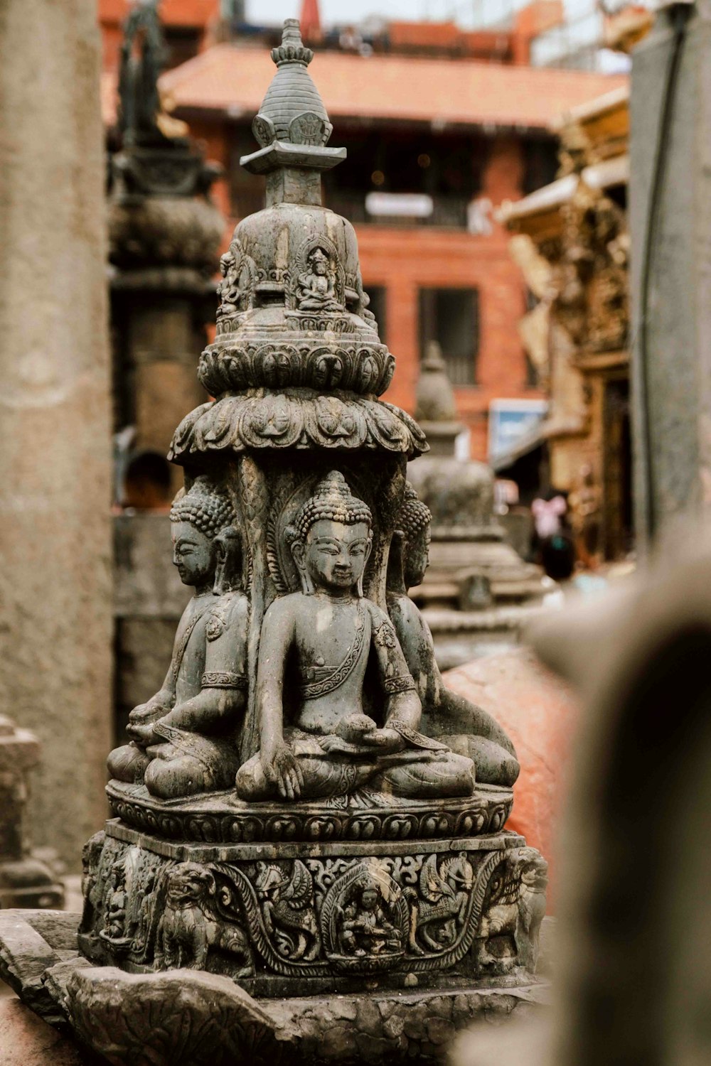 a statue of a buddha sitting on top of a stone pillar