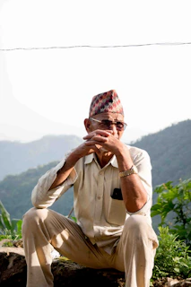 An elderly man checking his fall detection watch while gardening outdoors on a sunny day.
