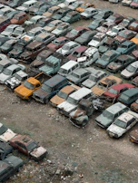 A variety of junk cars in different conditions waiting for removal.