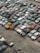 A large collection of old, rusting cars is tightly packed in an outdoor junkyard. The vehicles are in various states of disrepair, with peeling paint and visible rust. The ground around the cars is covered with dirt and scattered debris.