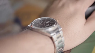 Close-up macro shot of a ddl watch showcasing its brushed stainless steel case and deep teal dial under soft light.