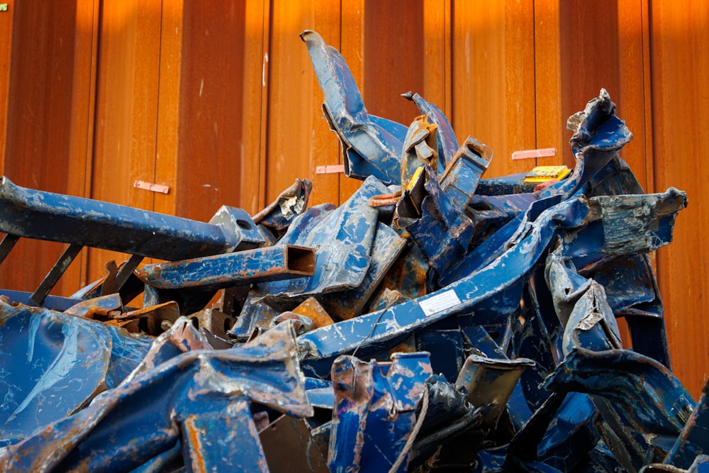 a pile of blue metal scrap next to a wooden wall