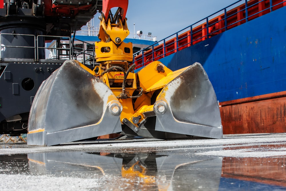 a yellow bulldozer sitting in front of a large ship