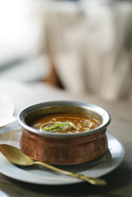 a bowl of soup on a plate with a spoon