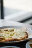 A close-up of freshly baked naan bread served with a side of rich curry.