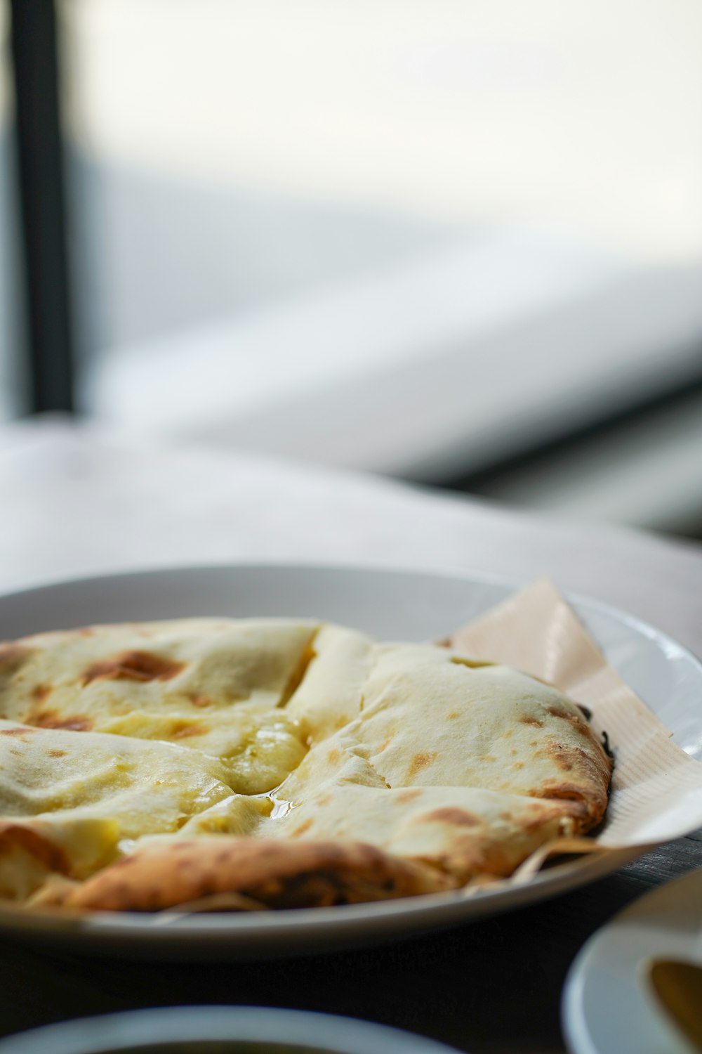 a white plate topped with a pizza on top of a table