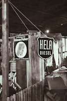 A rustic indoor setting with vintage signs, including one advertising diesel and another for a household product. There are wooden structures, a wicker basket, and assorted vintage items creating a retro atmosphere.