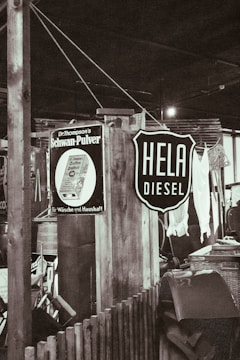 A rustic indoor setting with vintage signs, including one advertising diesel and another for a household product. There are wooden structures, a wicker basket, and assorted vintage items creating a retro atmosphere.