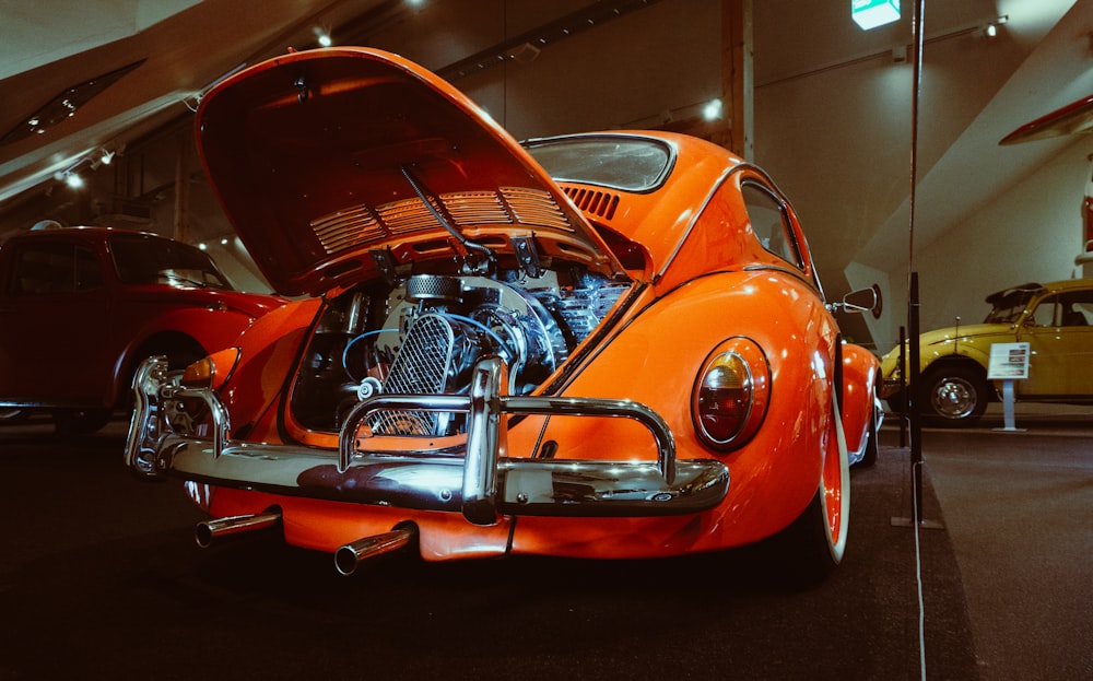 an orange vw bug is parked in a showroom