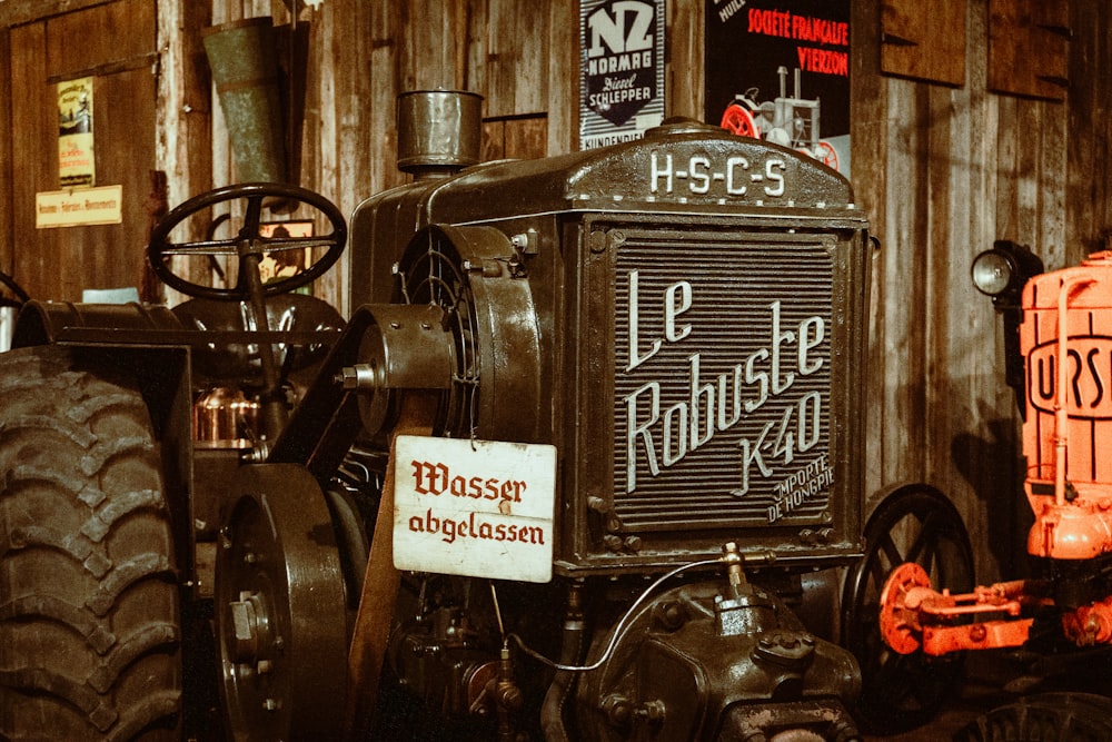 an old tractor is parked in front of a wooden building