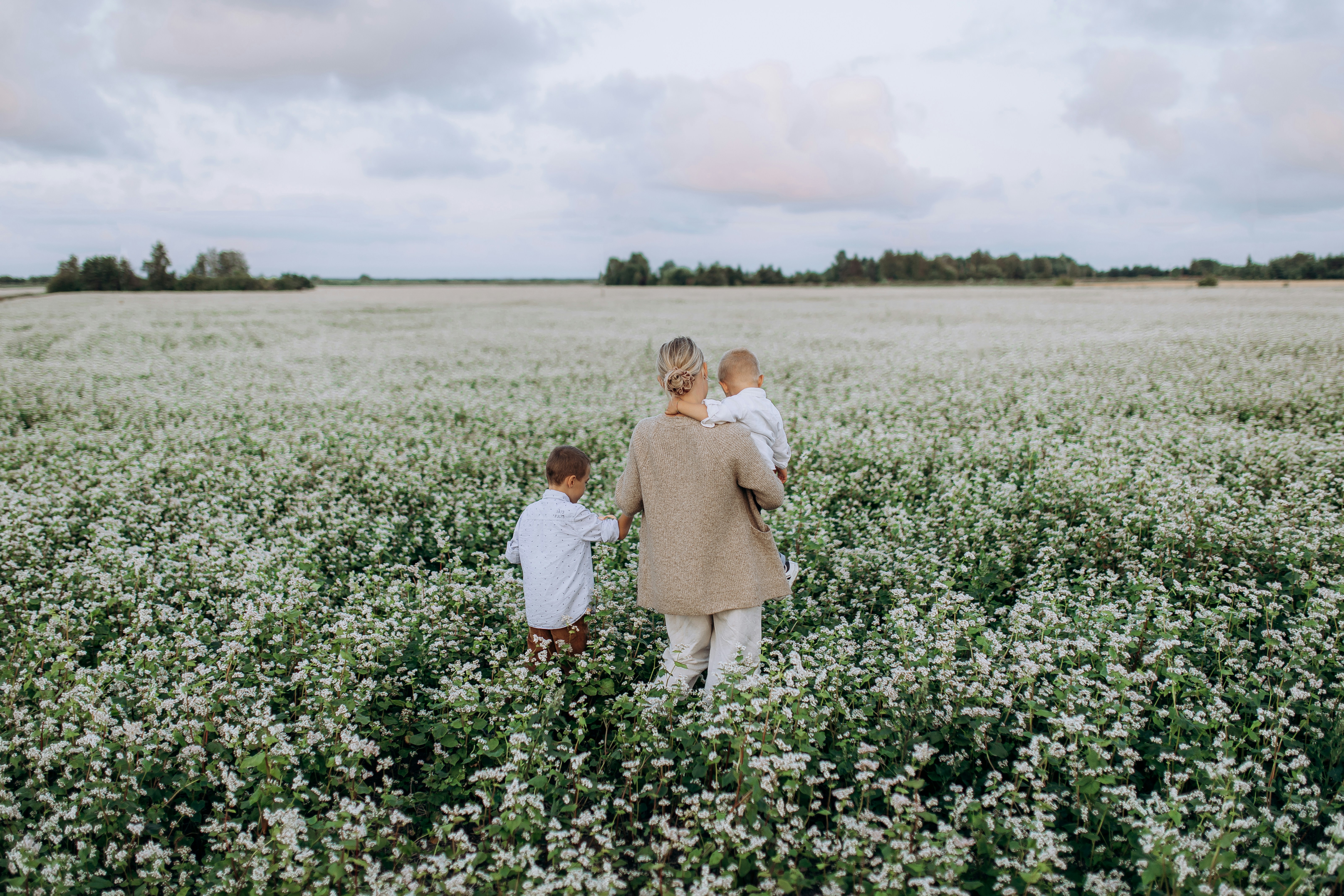 a woman and child walking through a field of flowers