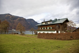 a house with a green roof next to a body of water