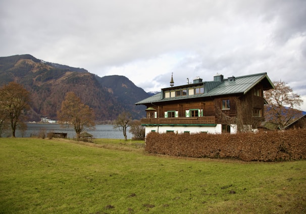 a house with a green roof next to a body of water