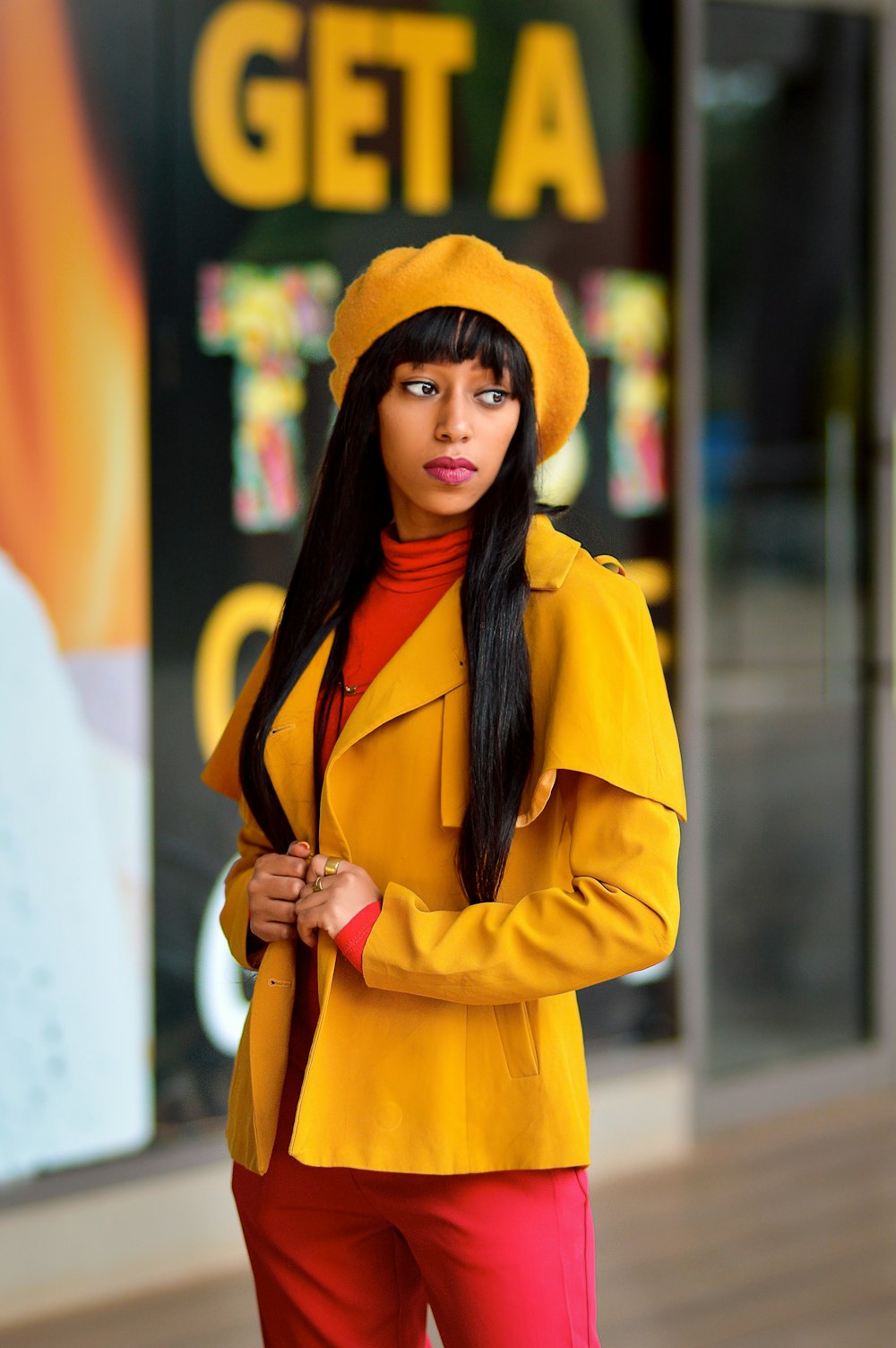 a woman in a yellow coat and red pants