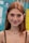 A young woman with long red hair, freckles, and large hoop earrings smiles gently towards the camera. She wears a black spaghetti strap top and a delicate necklace, standing in front of a colorful background featuring various blurred logos and text.