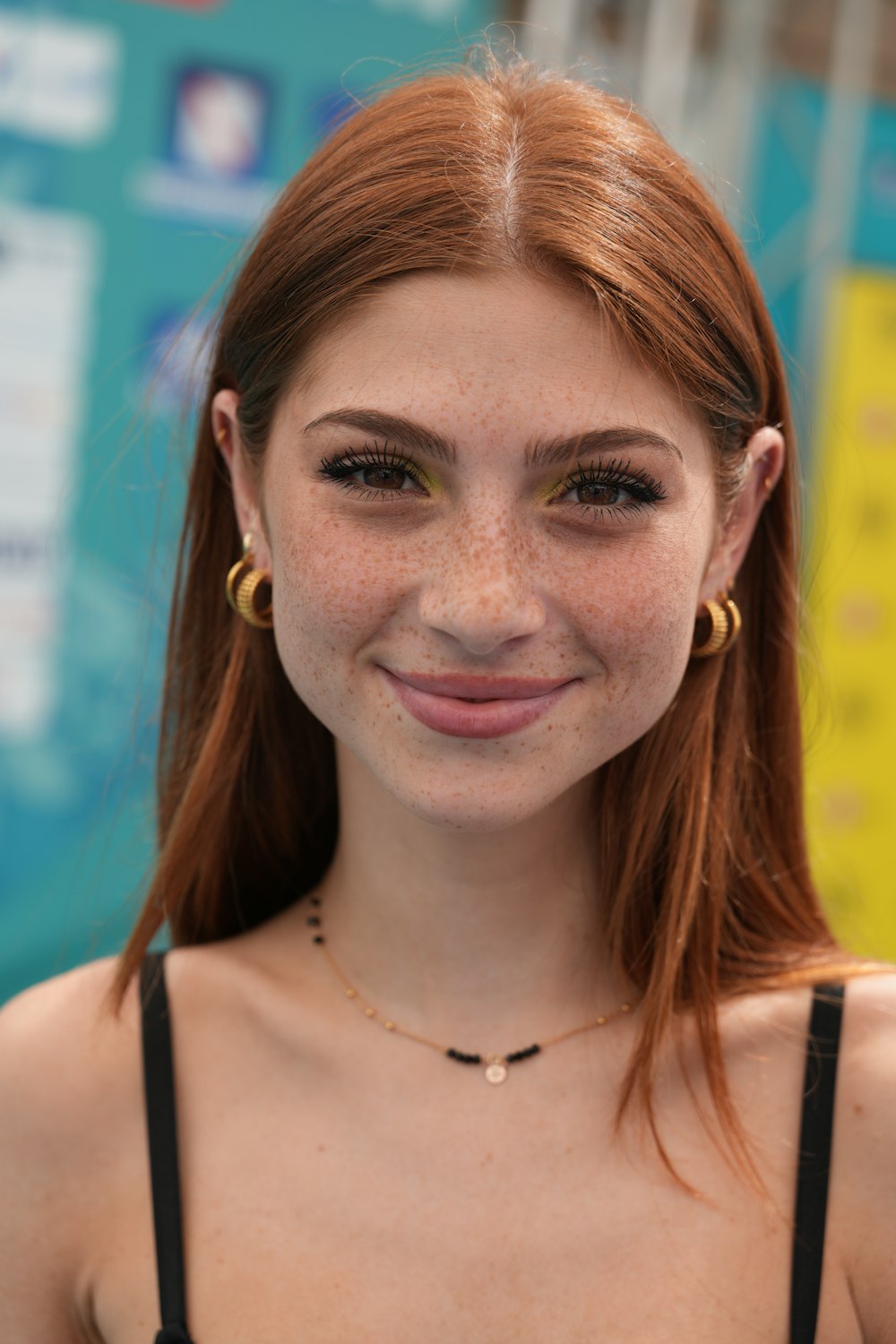 a woman with freckles and a black bra smiling