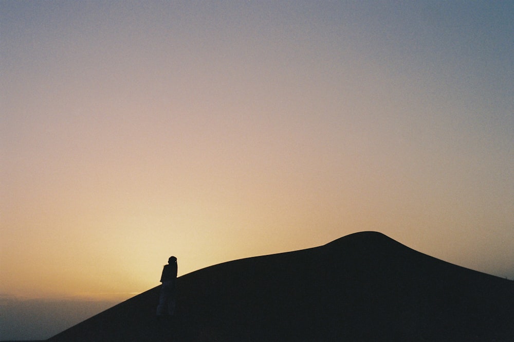 a person standing on top of a hill at sunset